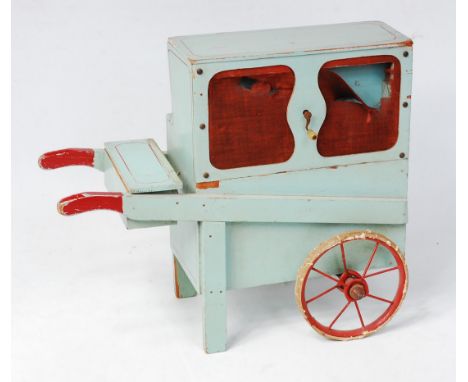 An early 20th century painted pine Organ Grinder, finished in light blue and red, with red spoked metal wheels, fitted with r