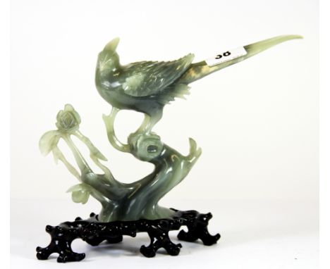 A beautiful Chinese carved mid 20th century jade/hardstone model of a golden pheasant on a carved wooden base. H. 20cms. Mino