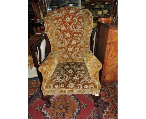 A George III style upholstered wing-back chair on short cabriole legs, carved with claw-on-ball; together with a feet Victori