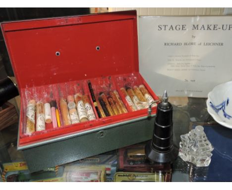 A vintage stage make-up box, an Art Deco bakelite atomiser and a glass scent bottle.