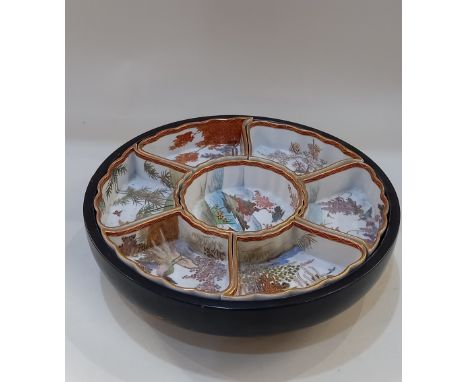 An Oriental lazy Susan with seven ceramic sectional dishes decorated with landscapes, in black painted wooden stand, 34.5cm d