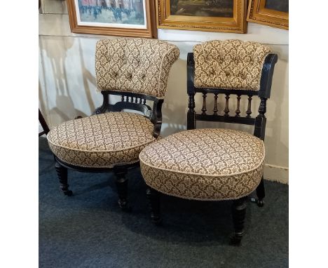 A pair of Victorian low chairs with button upholstered backs and ebonised frame on turned legs and castors  