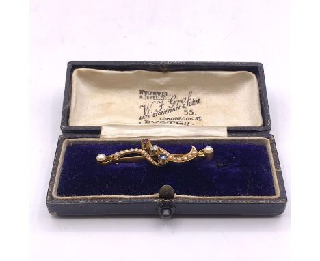 An untested gold brooch set with seed pearls and one of each a ruby, diamond and sapphire.