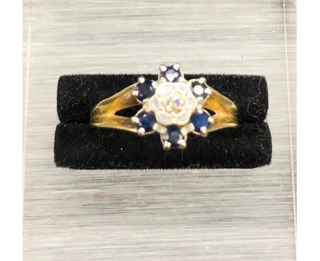 An 18 ct yellow gold Daisy style ring with central diamond and six sapphires (4.2g)