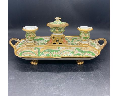 A porcelain desk stand with lidded inkwell to the center and two candlesticks with pen trays on both sides, decorated with gr