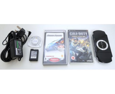 A Sony PSP with power cable and 3 games including F1 Grand Prix (loose), Ridge Racing, in case with manual, and Call of Duty 