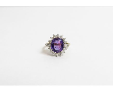 An amethyst and diamond cluster ring, stamped '18ct', the oval mixed cut stone, 10mm by 8mm by 4.3mm deep, enclosed by fourte