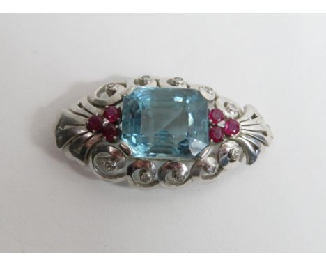 An aquamarine, ruby and diamond clip brooch, in unmarked white metal, the aquamarine measuring approximately 15.5 mm by 12.8 