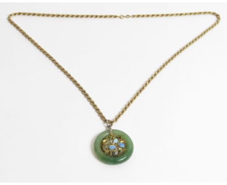 A jade and gem set pendant, the circle of jade enclosing a gilded setting with opals and small gem stones, 3.5 cm diameter, o