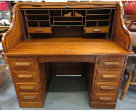 An early 20th century light oak roll top desk, with a tambour front with eight single short drawer section, 123cm high, 126cm
