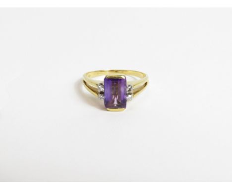 An amethyst ring, stamped '750', the rectangular cut stone with pairs of single cut diamonds to each shoulder, finger size R,