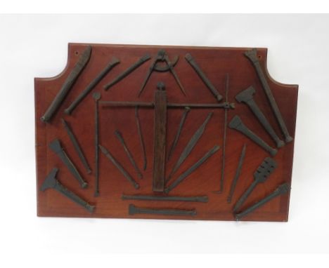 A collection of 20th century stonemasonry tools on a mahogany plaque