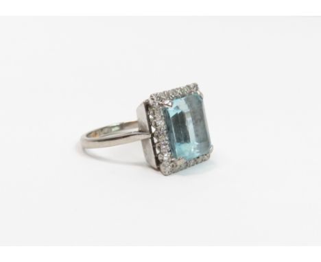 An aquamarine and diamond cluster ring, the white mount stamped '18ct', the step cut stone measuring approximately 11mm by 10