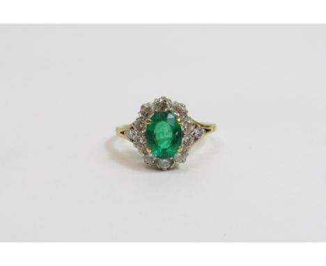 An emerald and diamond 18 carat gold cluster ring, the oval cut stone measuring approximately 7.9mm by 5.9mm by 4.2mm deep, e