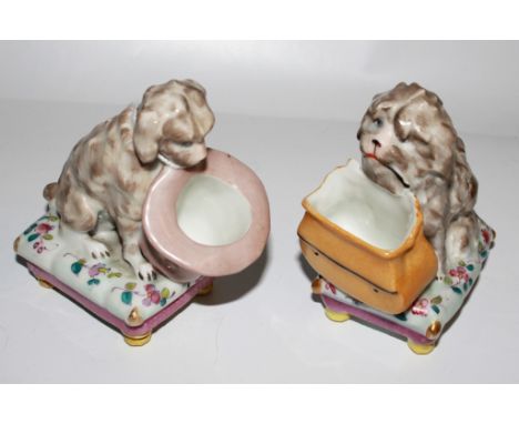 Two Dresden-style porcelain figurines in the form of little dogs on oblong bases, both 11cm high