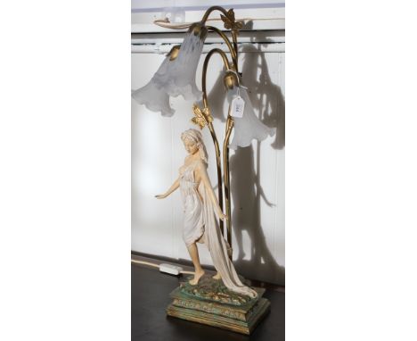 An Art Deco treble shade table lamp featuring and coquettish young lady in diaphanous robes on an oblong base fitted for elec