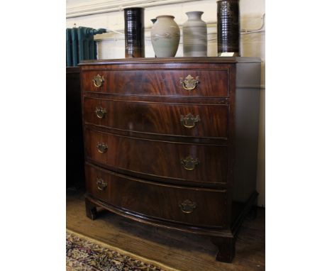 A Georgian-style mahogany bow fronted chest of four graduated drawers with metal drop handles and carved back plates, shaped 