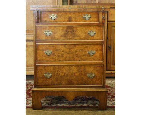 A walnut and mahogany chest of four graduated drawers in the Georgian style with fold over top, brass drop handles, raised on