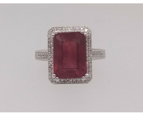 A 14k white gold and diamond ring set with an emerald cut ruby approx 7ct diamonds, approx 0.30ct total weight, size M.