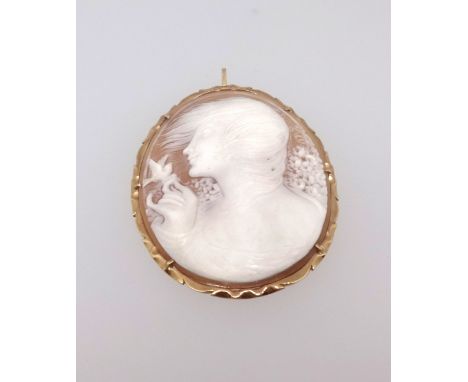 An antique cameo brooch with a portrait of a lady with a bird and flowing hair in a yellow metal brooch and pendant mount, he