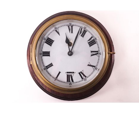 A brass cased ships timepiece on a mahogany panel with white enamel Roman dial, clock 18cm diameter, and the backboard 29cm d