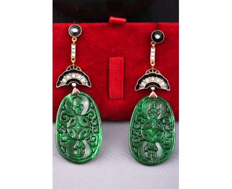A yellow metal pair of drop earrings. Each having a large oval pierced jade drop.  Further set with round brilliant cut diamo