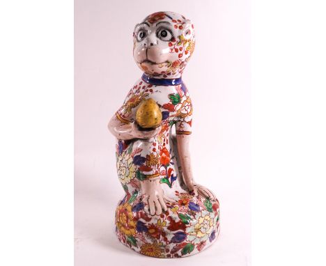 A ceramic figure of a crouching monkey decorated in the Imari palette, 28cm high