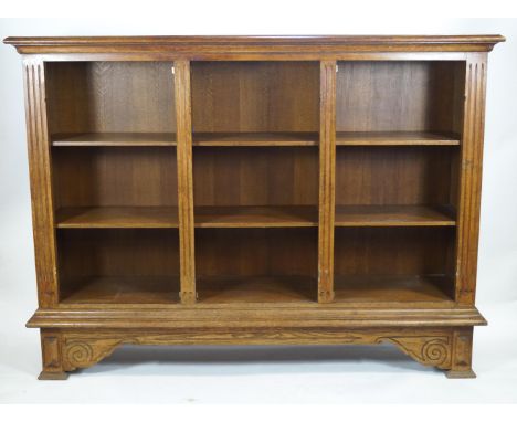 An oak open bookcase of large proportions with an edged plain rectangular top over three shelf units on a cornice base, raise