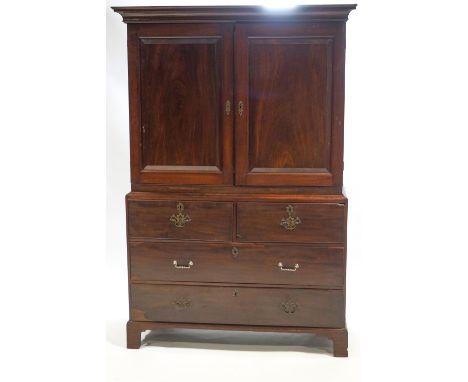 An 18th century mahogany linen press style cabinet on chest, the top with a projecting frieze over two fielded panel doors, t