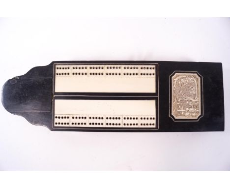 A late 19th century ebony cribbage board inset with a Chinese carved panel, the sliding over opening to reveal three cribbage