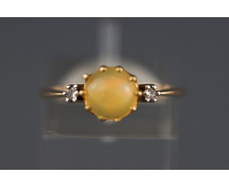 A yellow metal three stone ring set with a cabochon cut opal and two diamonds. Hallmarked 9ct gold, Birmingham. Size N 1.8 gr