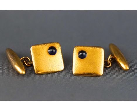 A yellow metal pair of chain and t-bar cufflinks. Cushion design each set with a cabochon dark blue sapphire Stamped 15ct. 7.