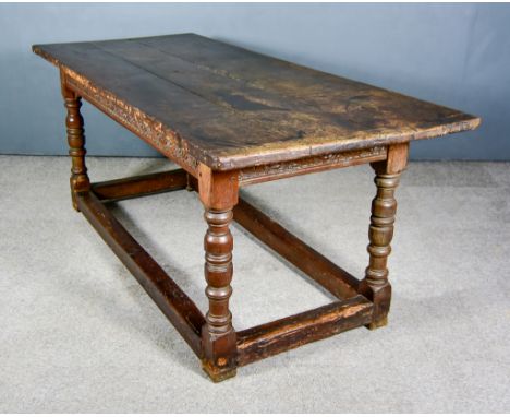 An Old Oak Refectory Table, with three plank cleated top, the frieze carved with scrolling floral ornament, on baluster turne