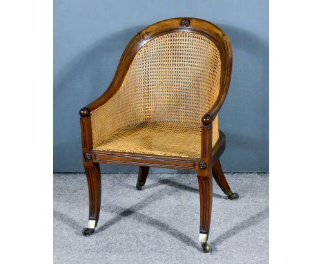 An Early 19th Century Mahogany Framed Bergere Easy Chair, the tub-shaped back with leaf cresting, caned back and seat, on sab