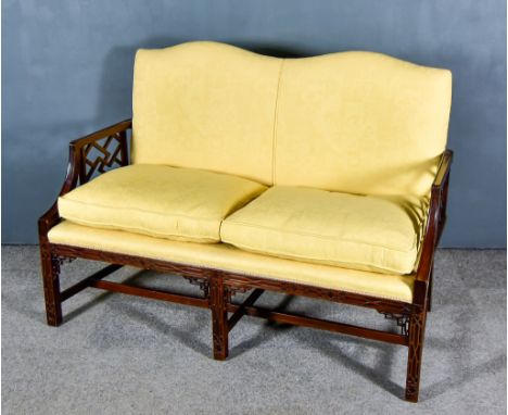 An Early 20th Century Mahogany Two Seat Settee of "Chinese Chippendale" Design, the back and seat upholstered in old gold dam