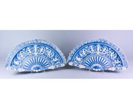 A Pair of Continental Bisque Porcelain Blue and White Fan Plates, moulded and decorated in white with dancing cherubs and scr