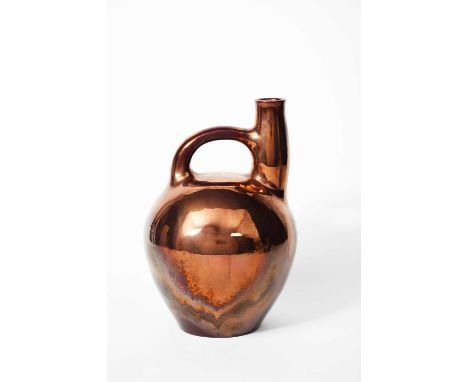 A large Carter's Poole Pottery lustre ewer, ovoid with cylindrical neck and over-slung handle, covered in a ruby lustre glaze