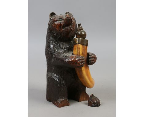 A table top lighter formed as a carved wood Black Forest bear with glass eyes holding a wild boar tusk.