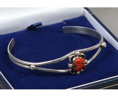 An openwork silver bangle set with coral.