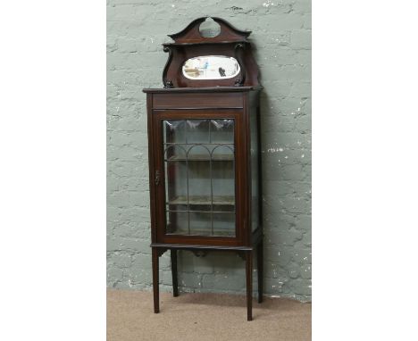 An Edwardian mahogany display cabinet with mirror back swan pediment, a lead glazed door with cushion glass and strung inlay,