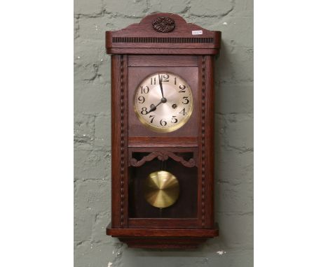 A oak cased eight day wall clock striking on a gong.