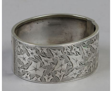 A Victorian silver bangle engraved with stylized leaves.