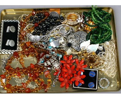 A tin of assorted costume jewellery including enamel cufflinks including amber and coral effect pieces.