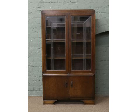 An oak display cabinet with leaded glass doors over cupboard base raised on bracket feet.