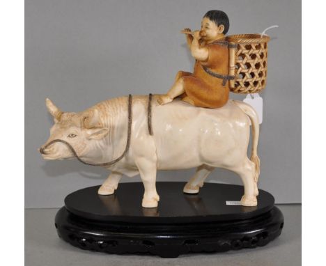 Antique Japanese carved ivory boy on ox figure depicting a boy with wood basket on his shoulders, playing a flute, and riding