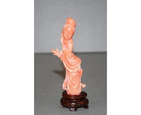 Chinese carved coral figurine of a Guanyin on carved wood stand. Height 11cm approx (including stand).