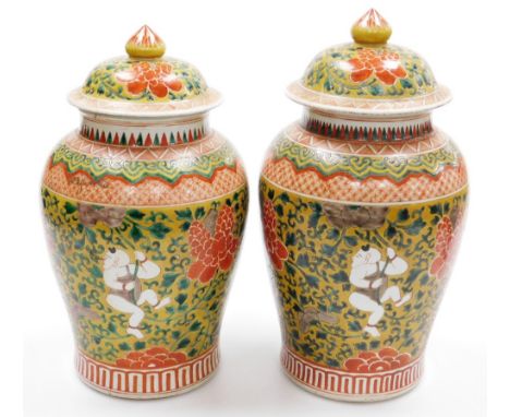 A pair of Chinese porcelain baluster jar and covers, decorated with boys clambering among scrolling peonies, six character Ka