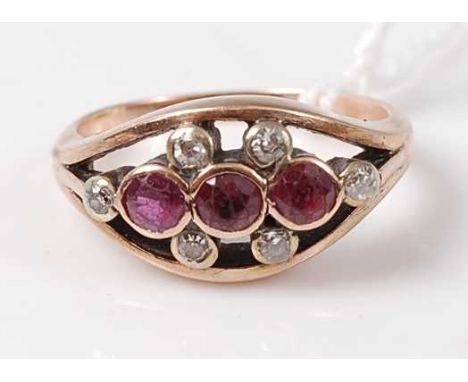 A 9ct gold, ruby and diamond dress ring, the elliptical setting centre set with three round cut rubies in rubover settings,  