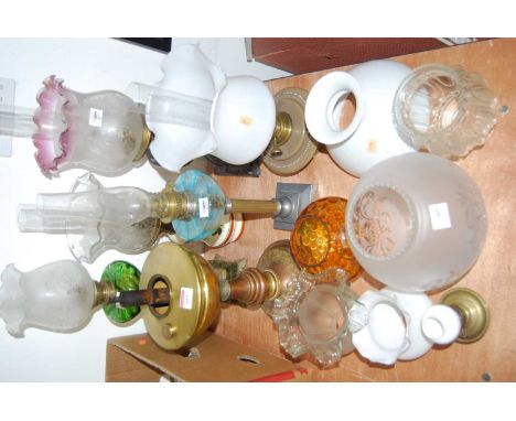 A collection of Victorian and later oil lamps and various lamp shades