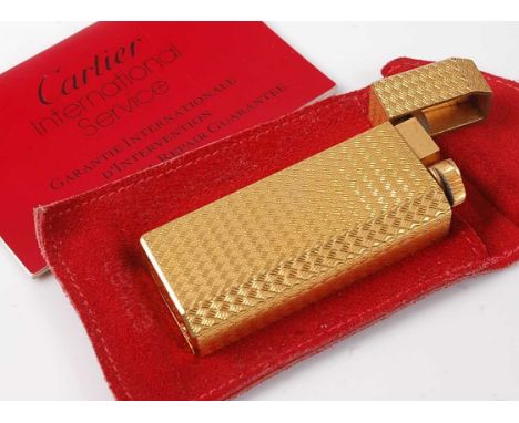 A Must de Cartier engine turned gold plated cased pocket cigarette lighter, serial number A72661, with suede pouch and servic